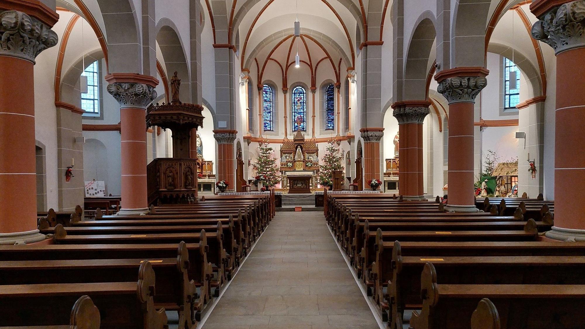 Rechts und links neben einem leeren Gang zum Altar stehen leere Kirchenbänke.
