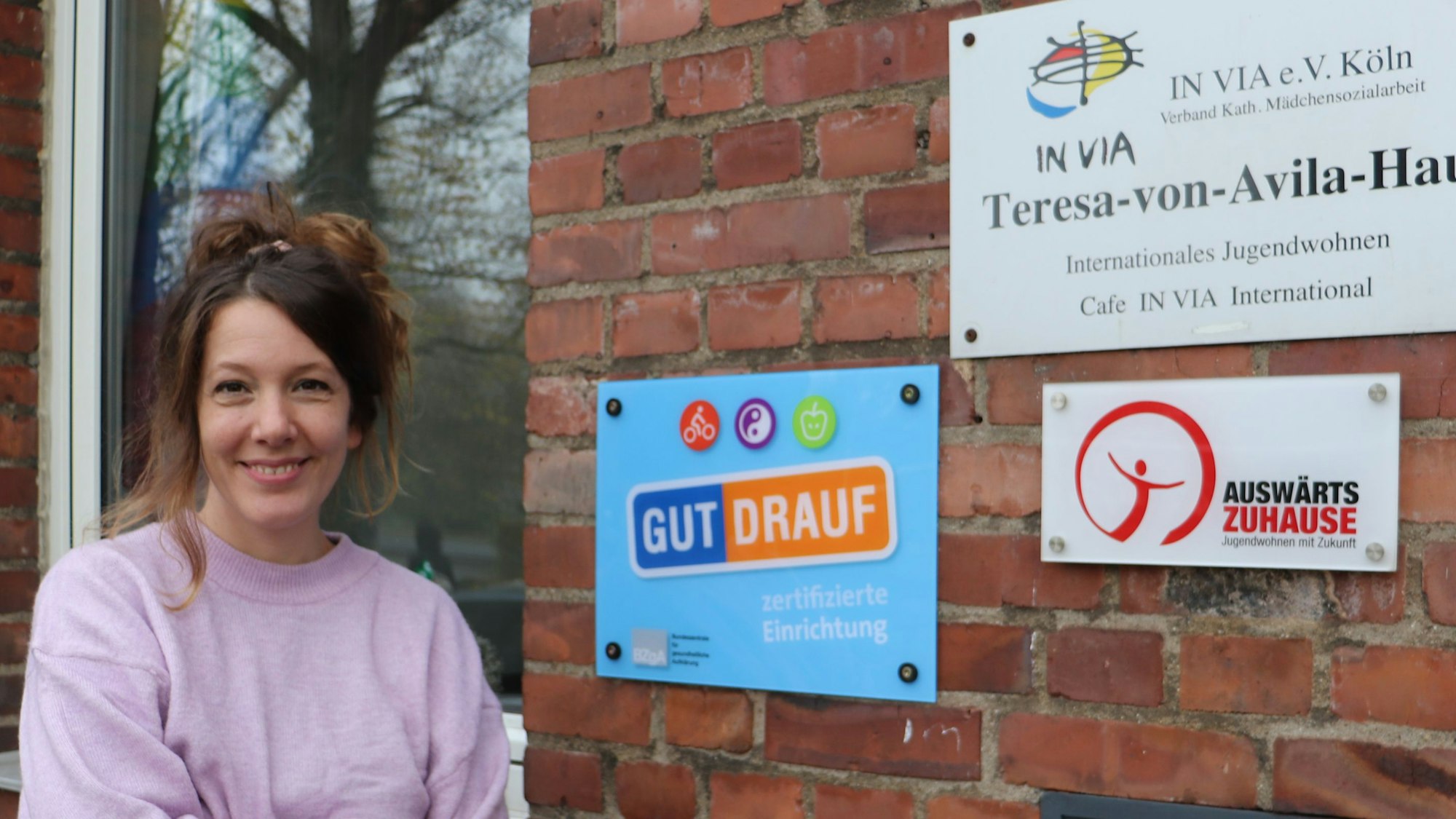 Sozialpädagogin Sandy Müller steht vor dem „In via“-Mädchenwohnheim, an dessen Wand die Zertifikate hängen.
