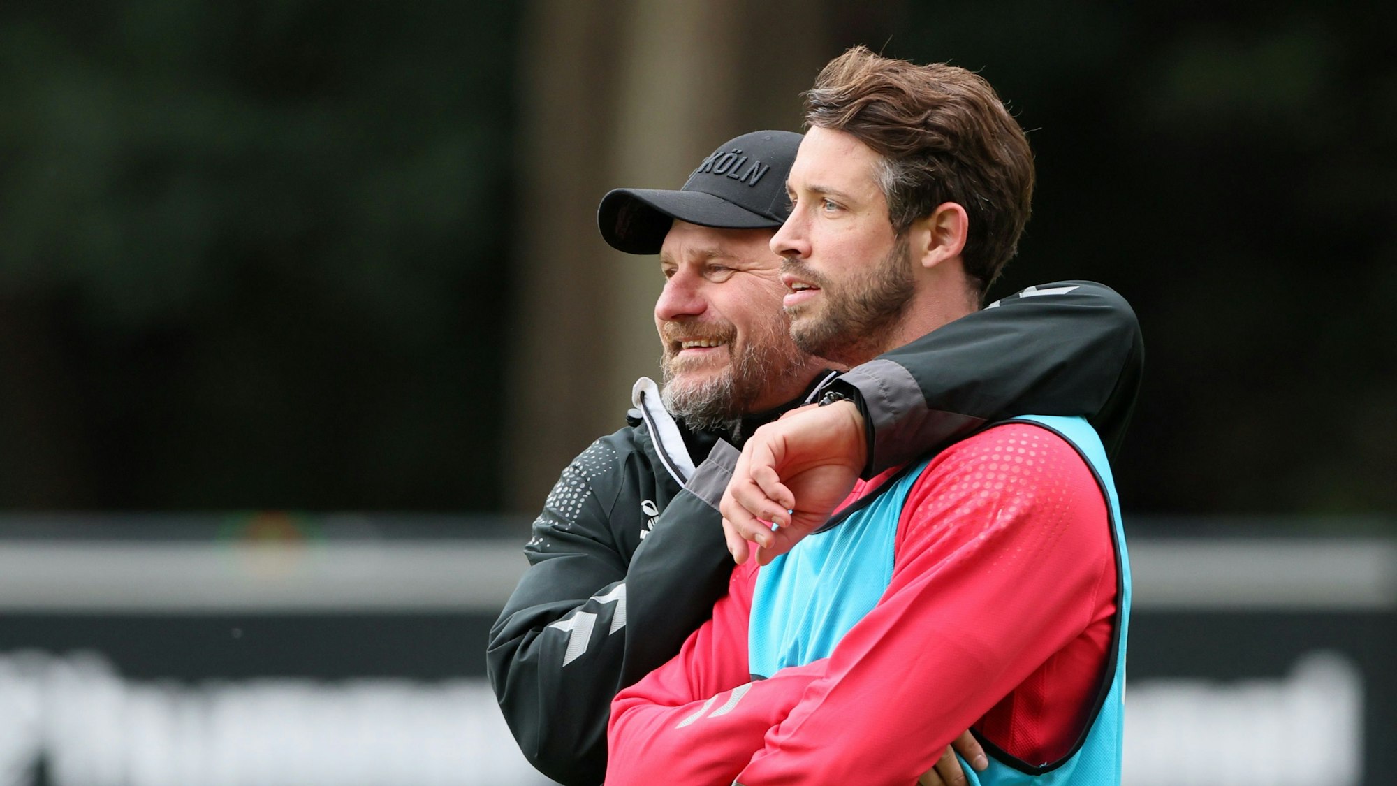 Mark Uth steht neben Steffen Baumgart, beide lächeln.