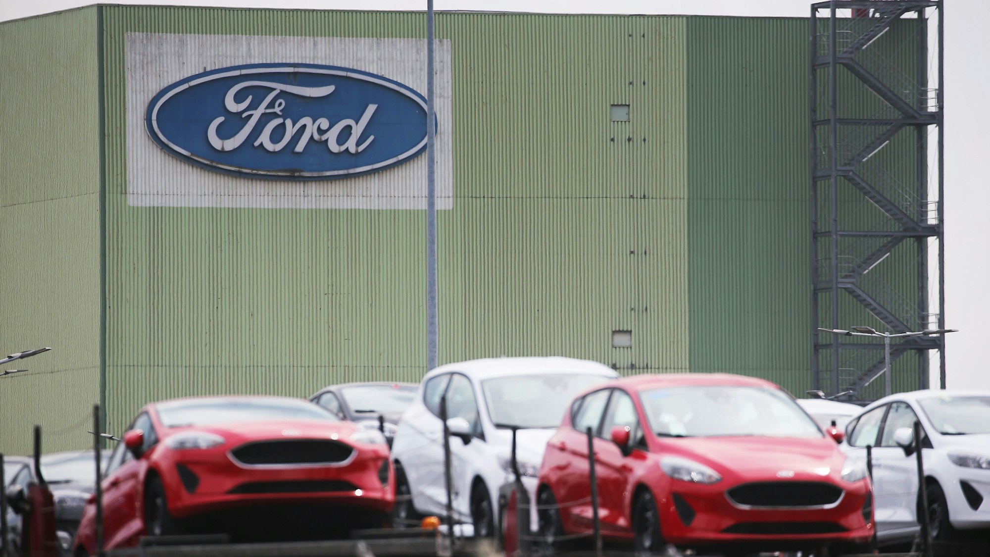 Neu gebaute Autos stehen auf Lastwagen vor dem Ford Werk.