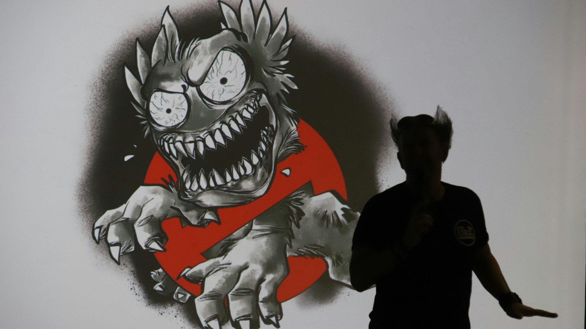 Der Schattenriss eines Mannes steht vor einem gezeichneten Monster, das große Krallen, viele Zähne und aufgerissene, geäderte Augen hat.