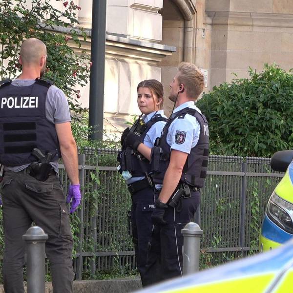 Mehrere Polizisten stehen um einen festgenommenen Mann herum.
