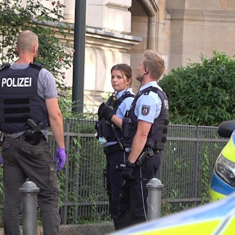 Mehrere Polizisten stehen um einen festgenommenen Mann herum.