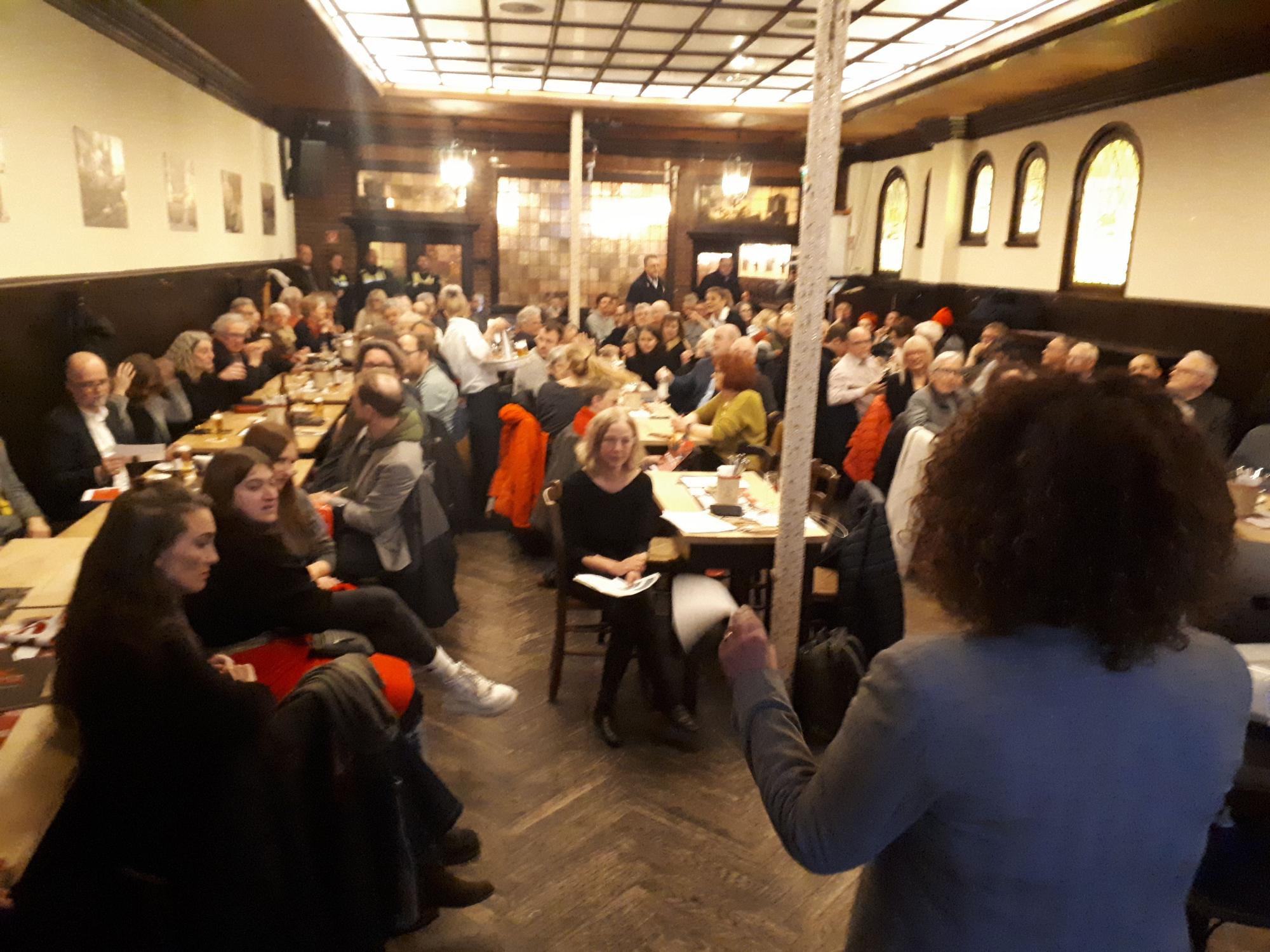 In einem Raum in einem Brauhaus sitzen viele Menschen an Tischen.