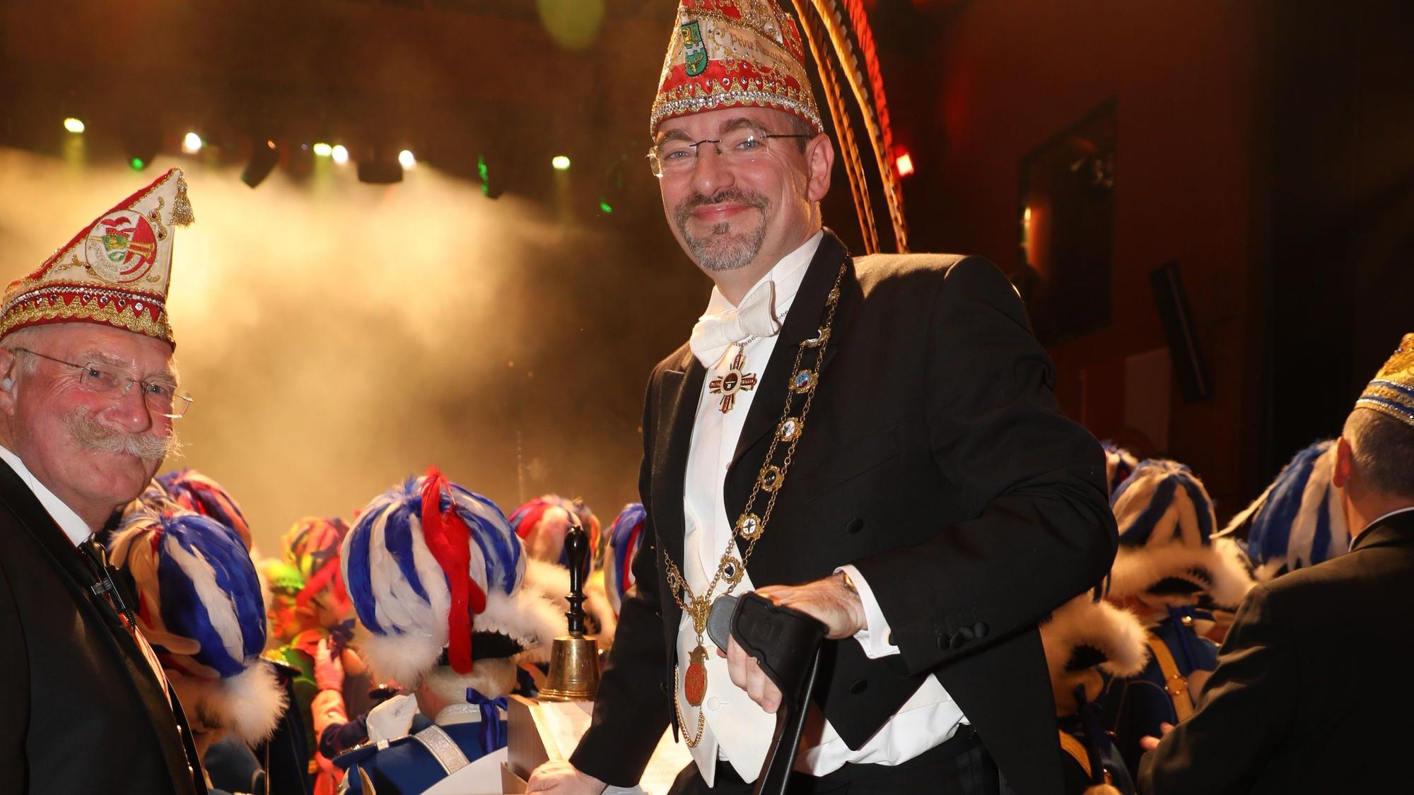 Präsident Alexander Pfister stützt sich auf eine Krücke hinterm Elferratstisch. Im Hintergrund ist der Saal zu sehen.