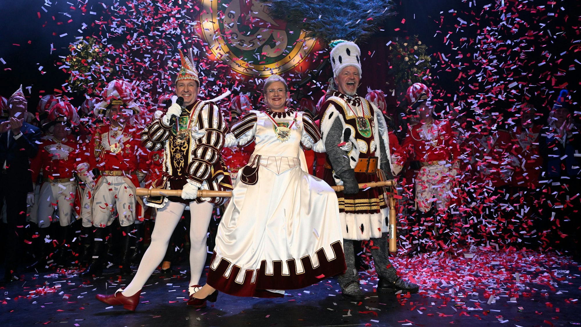 Das Bergisch Gladbacher Dreigestirn steht im Konfettiregen auf der Bühne.