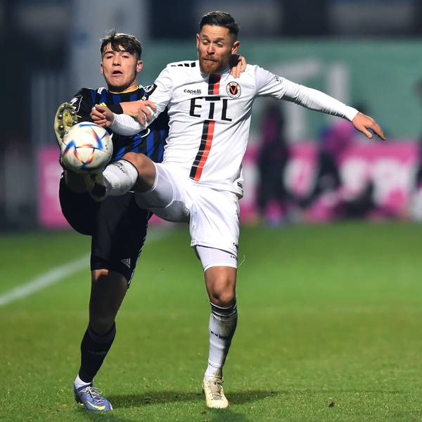 Ein Fußballspieler hält seinen Gegner im Zweikampf am Arm und an der Schulter fest.