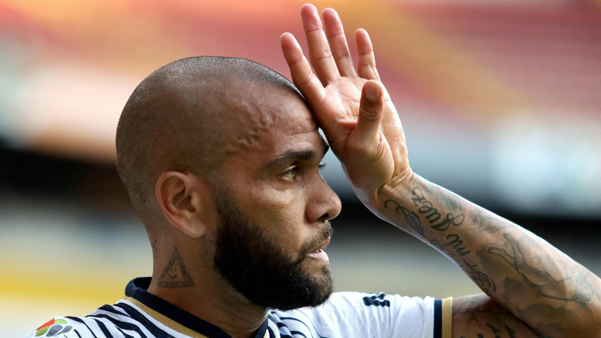 Dani Alves sieht in die Ferne und hält sich eine Hand an den Kopf.