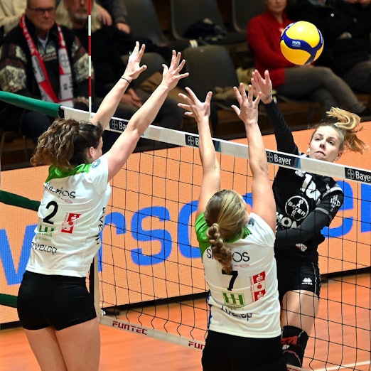 Eine Volleyballspielerin schlägt den Ball am gegnerischen Block vorbei.