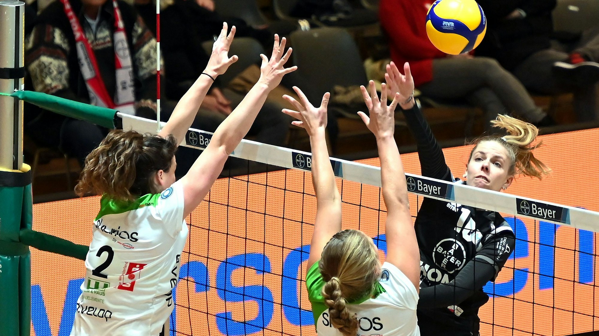 Eine Volleyballspielerin schlägt den Ball am gegnerischen Block vorbei.