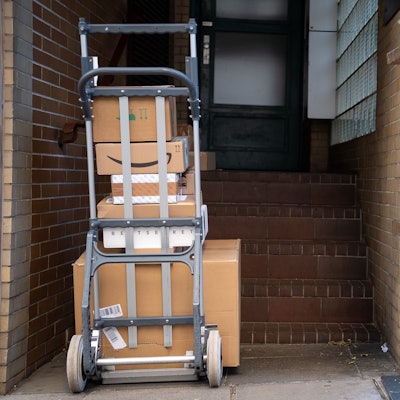 Man sieht einen Wagen mit Paketen vor einer Haustüre stehen.