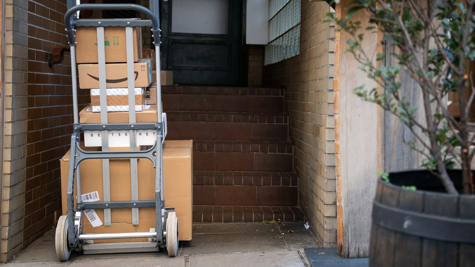 Man sieht einen Wagen mit Paketen vor einer Haustüre stehen.