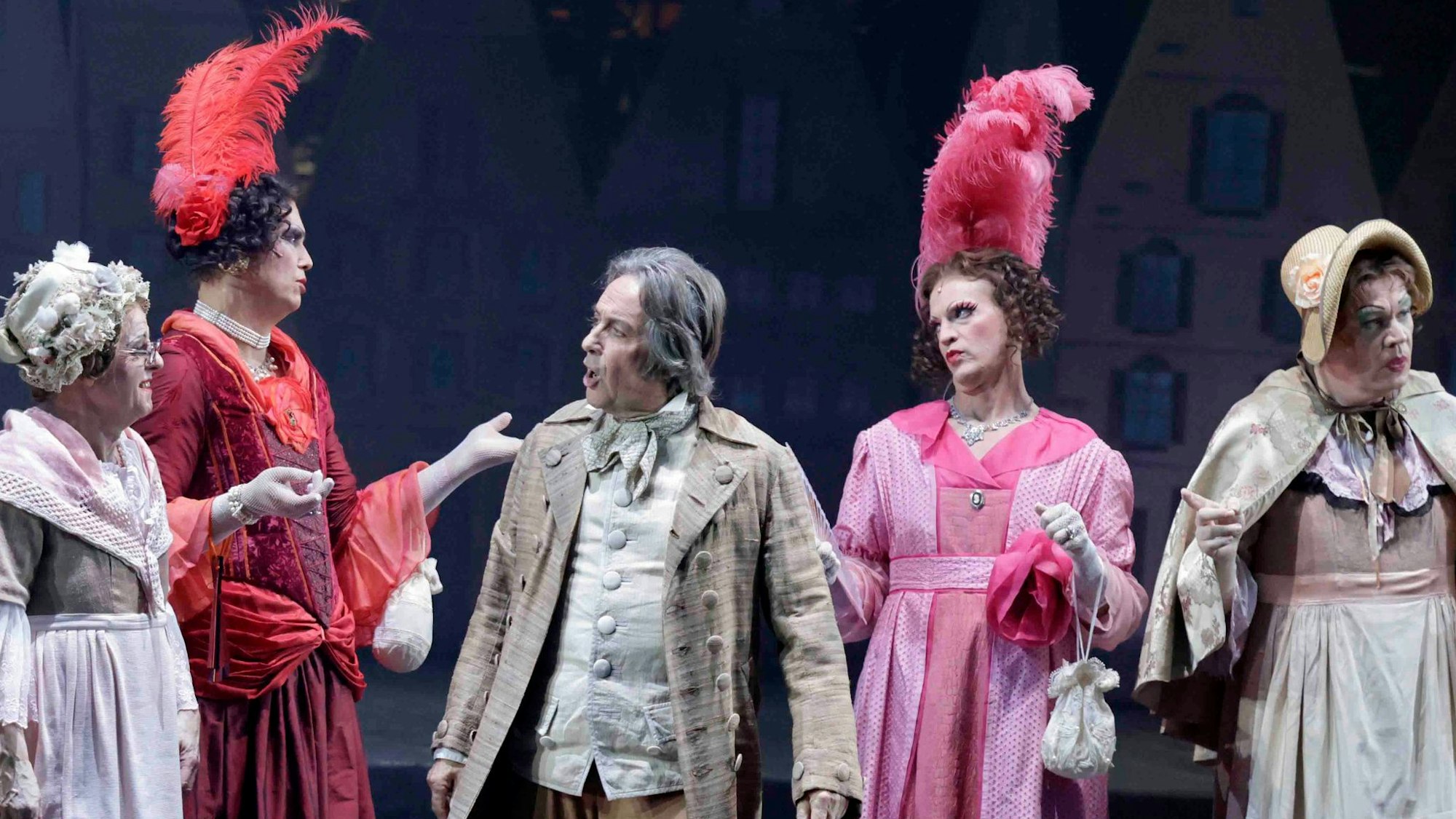 Verkleidete Schauspieler stehen auf der Bühne. Sie tragen zum Teil Federschmuck oder Hüte.