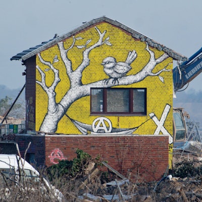 Ein Bagger reißt ein bemaltes Haus in Lützerath ab.