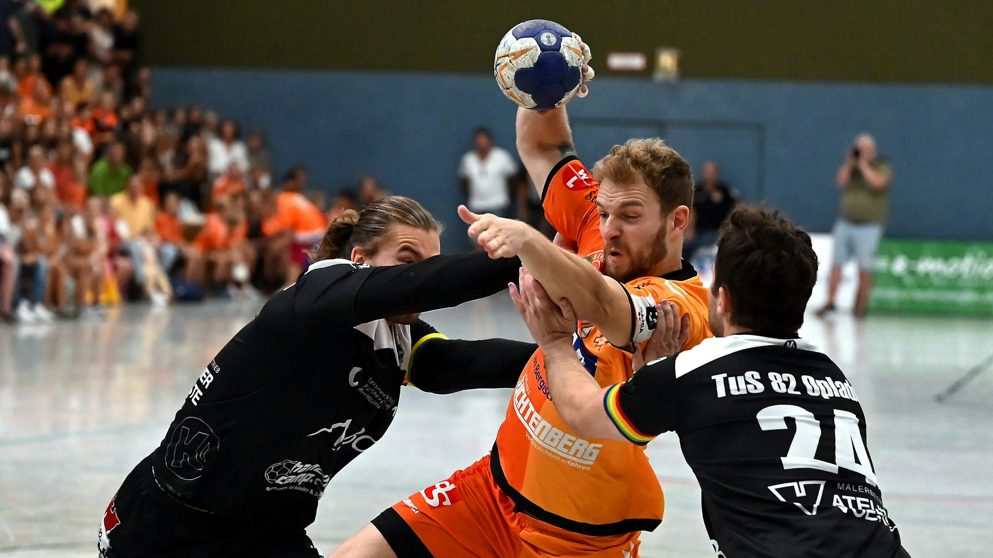 Ein Handballspieler setzt sich gegen zwei Gegner durch.