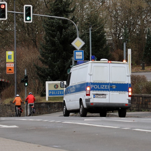 Ein Polizeifahrzeug steht in Bergisch Gladbach an einer Einmündung, an der ein Polizei-Schild steht.
