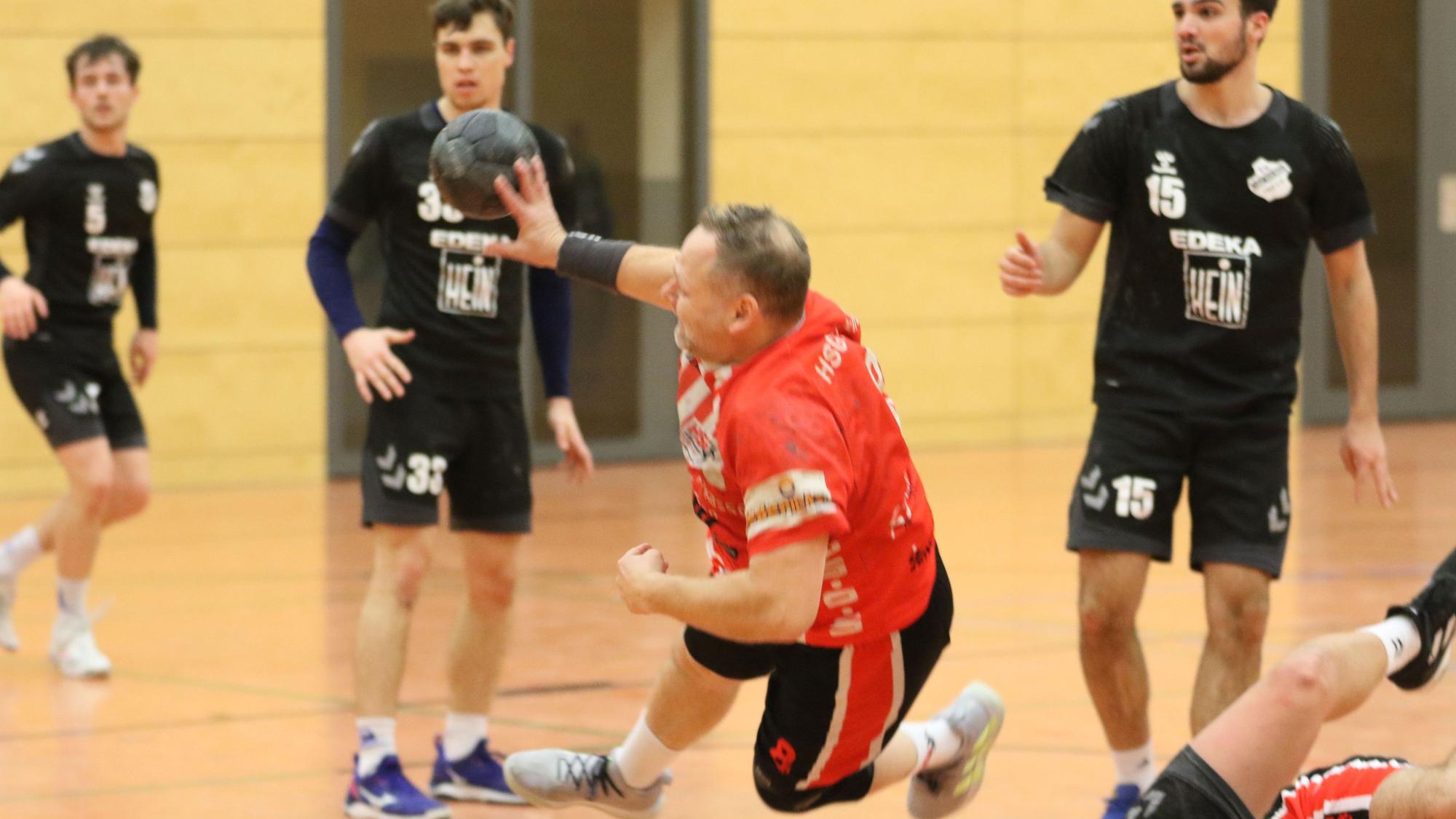 Stefan Tuitje, Trainer der HSG Euskirchen, ist beim Wurf von gegnerischen Spielern umring.