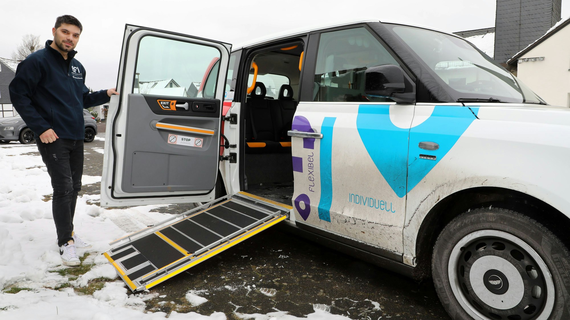 Fahrer Sercan Önen steht neben einem „Efi“-Auf-Abruf-Taxi mit ausgefahrener Rampe.