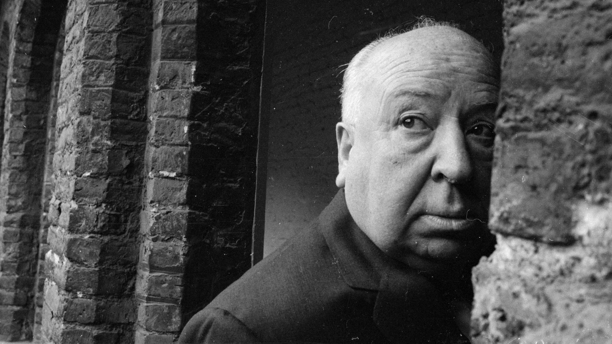 Alfred Hitchcock schaut an einer Wand vorbei.