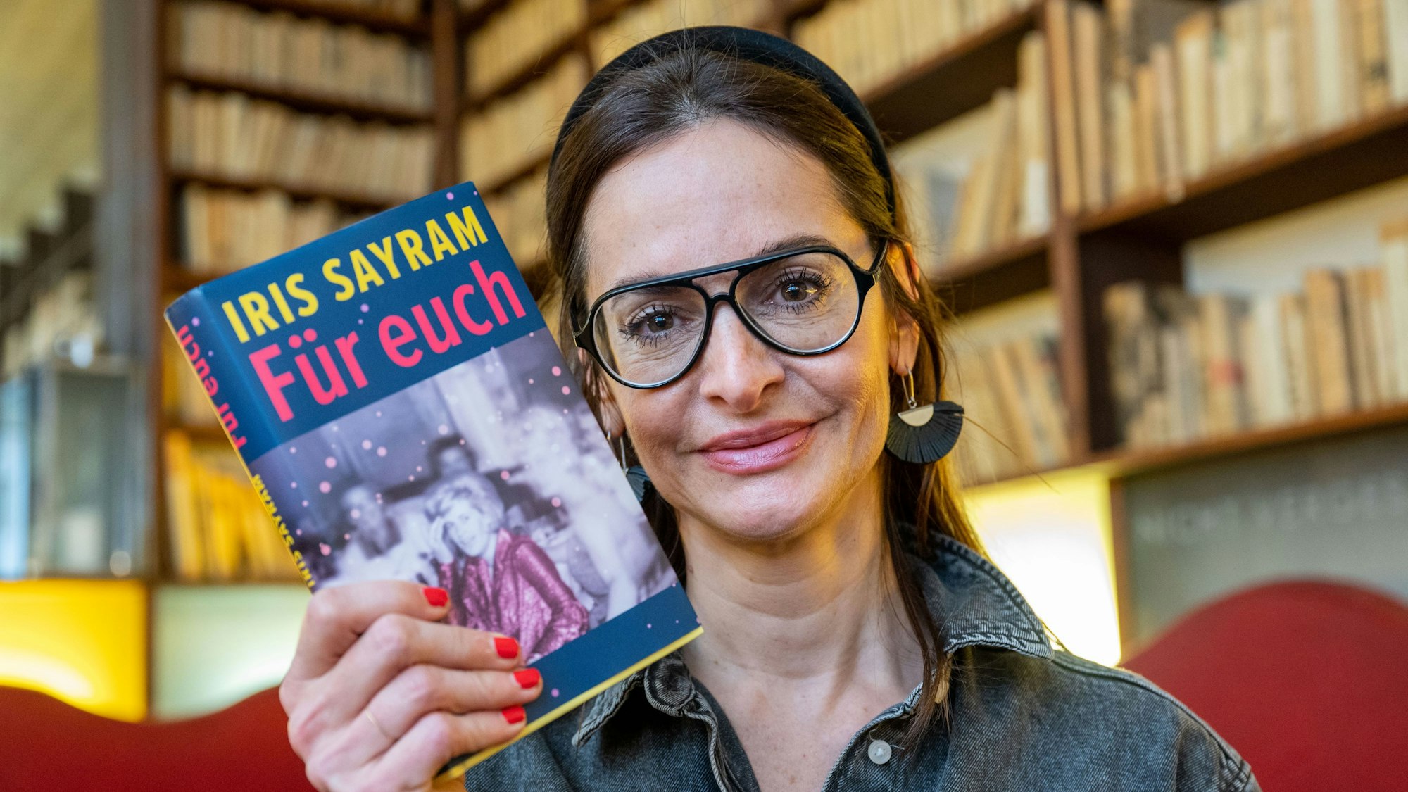 Sayram mit Bücherregalen im Hintergrund.