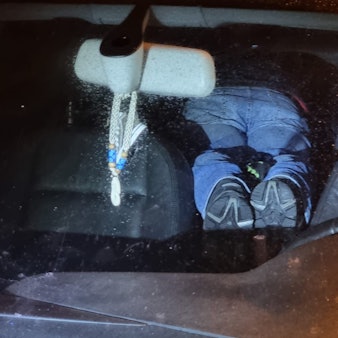 Zwei Männer liegen auf dem Bauch im Auto.