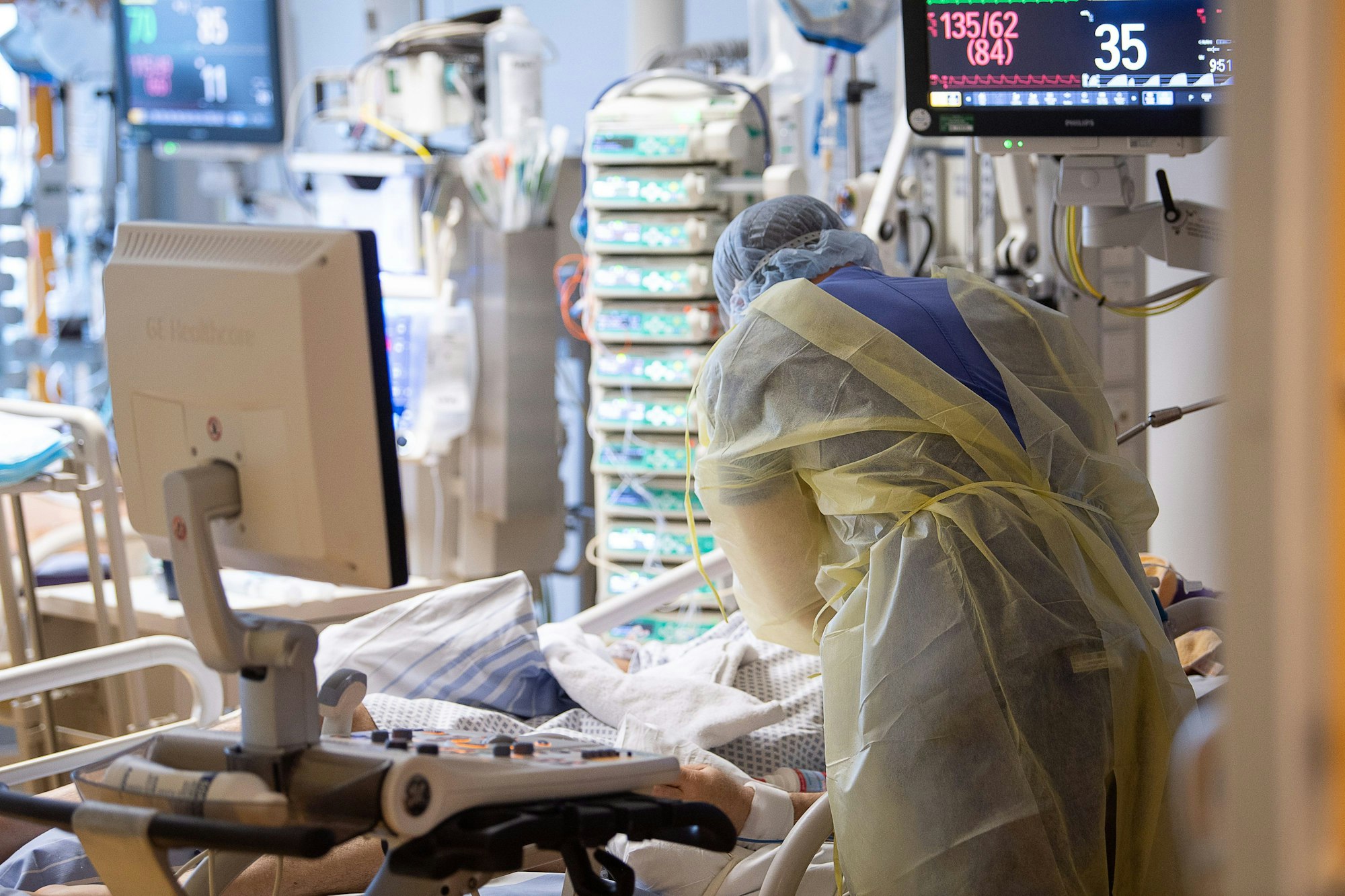 Eine Pflegerin beugt sich über einen Patienten in einem Krankenhaus.