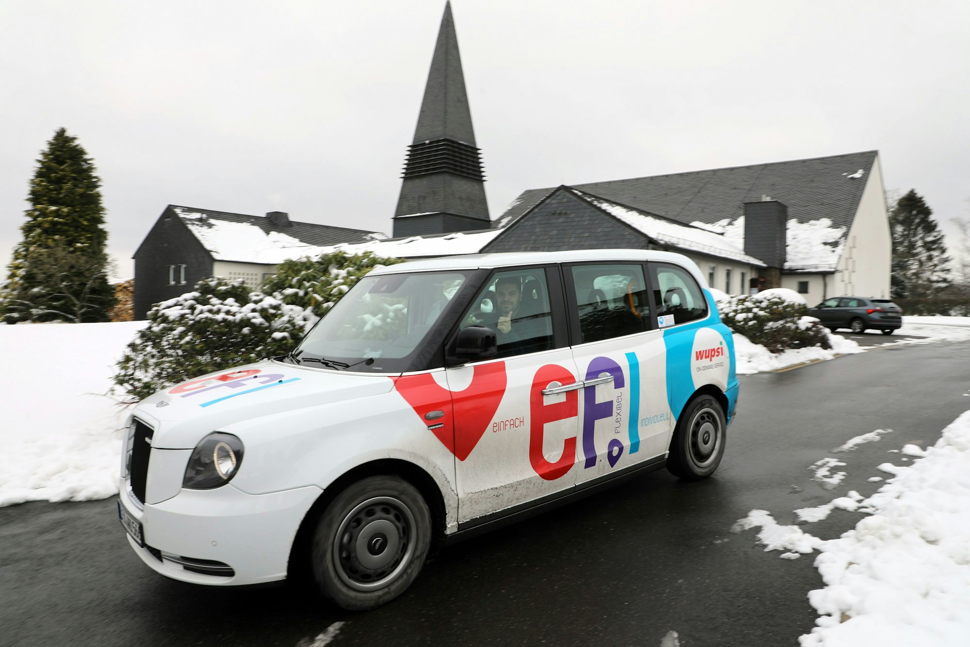Ein Efi-Fahrzeug des Typs London-Taxis fährt durch eine Straße, rundherum liegt Schnee.