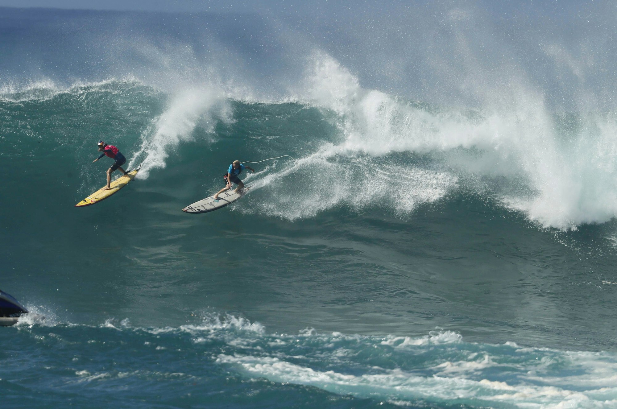 Justine Dupont und Keala Kennelly reiten gemeinsam eine große Welle während des Eddie Aikau Big Wave Invitational in der Waimea Bay.