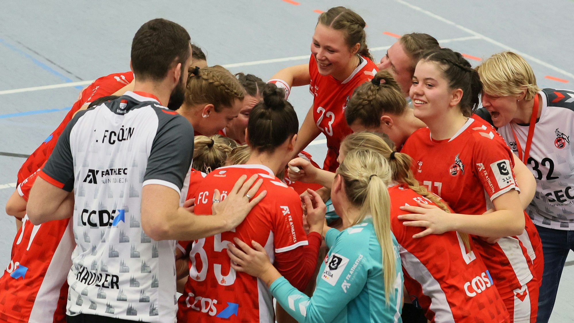 Ein Frauen-Handballteam steht im Kreis zusammen und freut sich über einen Sieg.