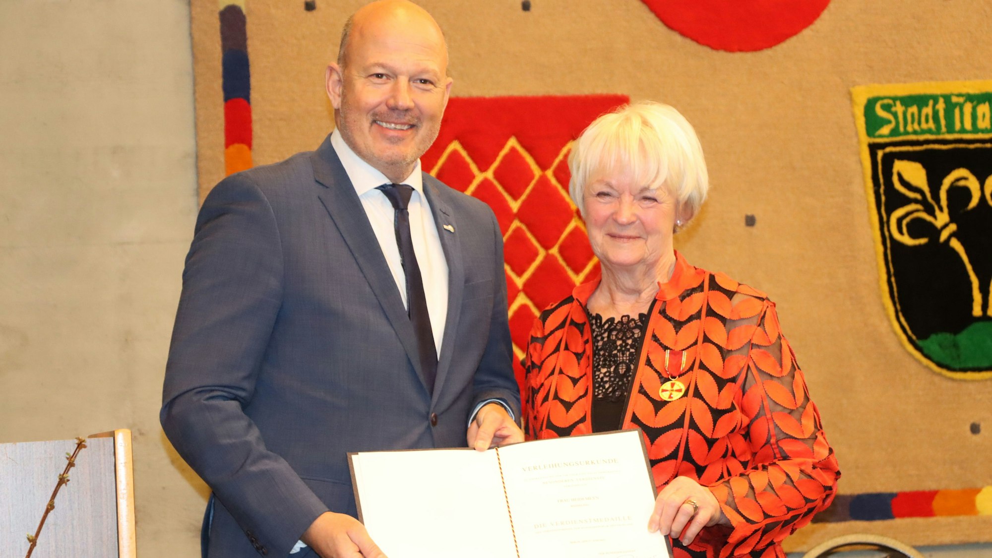 Im Auftrag des Bundespräsidenten Frank-Walter Steinmeier ehrte Landrat Frank Rock die Wesselinger SPD-Frau Heidi Meyn. Beide halten die Urkunde in die Kamera.