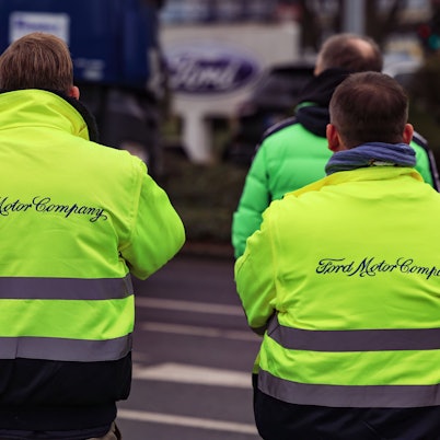 Mitarbeiter von Ford stehen vor dem Werksgelände.