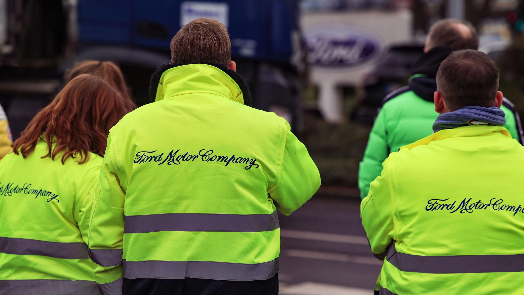 Mitarbeiter von Ford stehen vor dem Werksgelände.