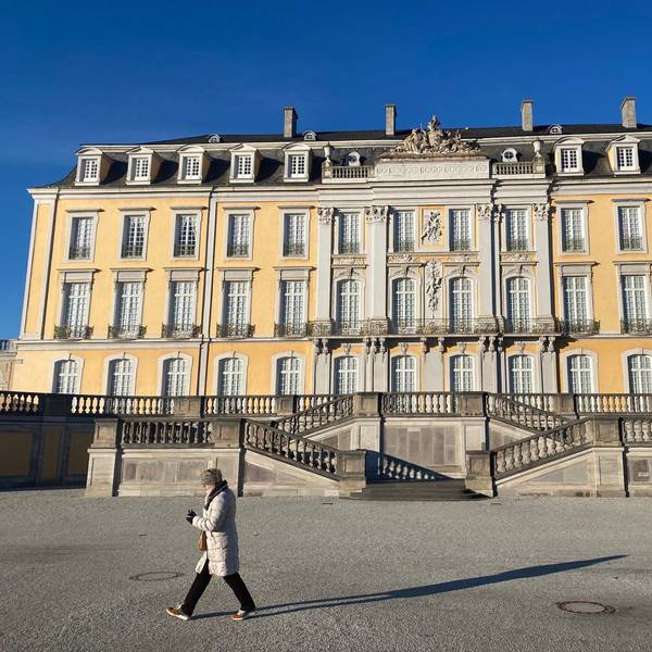 Eine Frau macht einen Spaziergang durch den Brühler Schlosspark. Im Hintergrund ist das Schloss zu sehen.