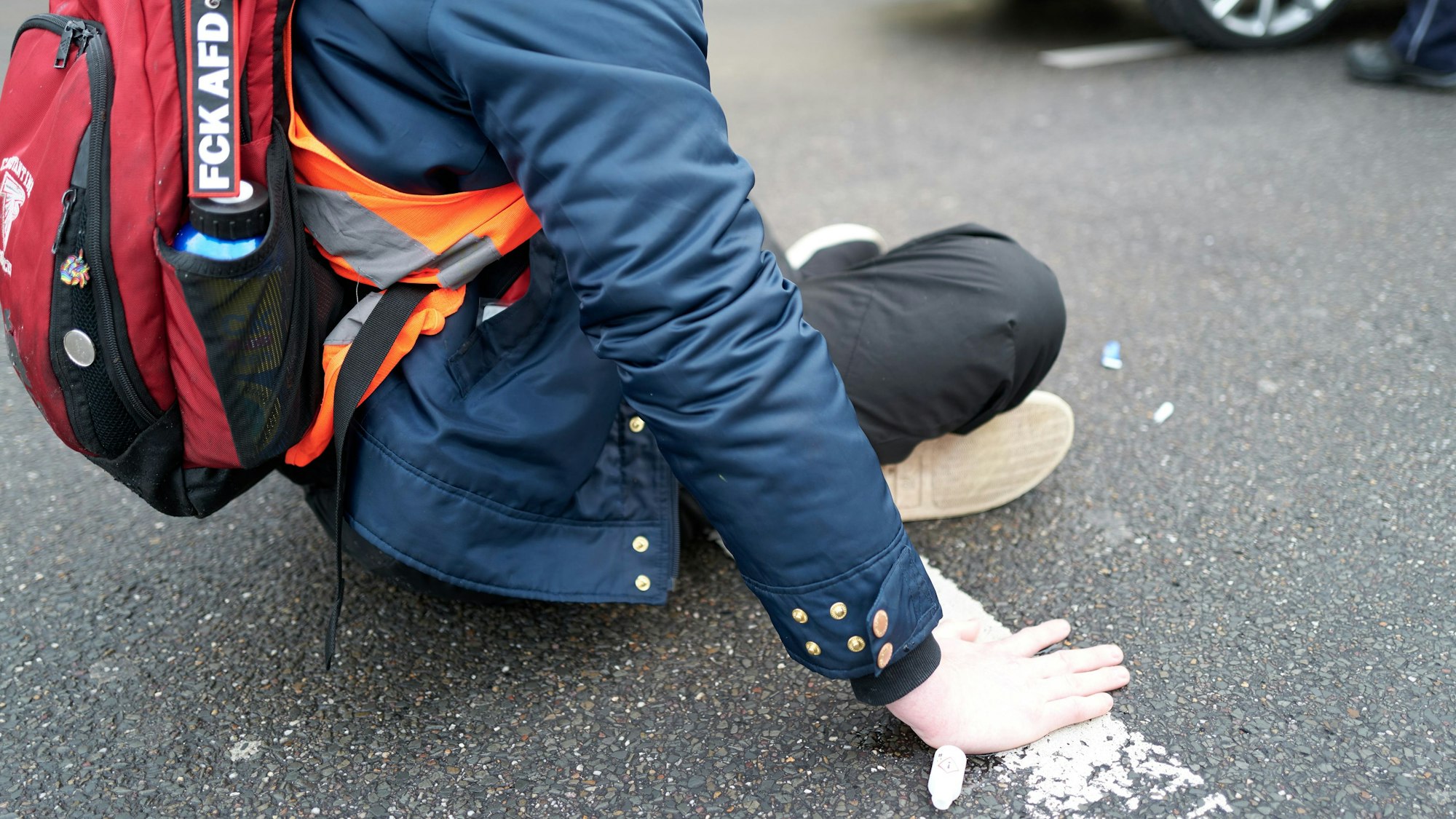 Ein Aktivist der „Letzten Generation“ kleben sich auf der Fahrbahn fest.