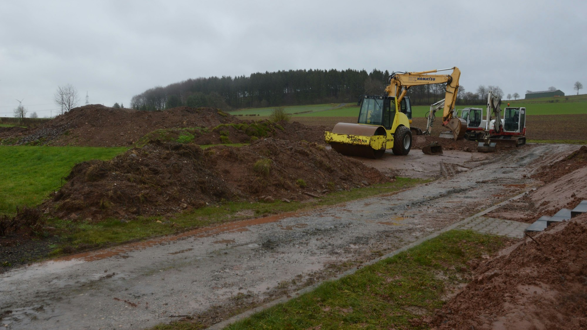 Baumaschinen stehen auf einem Acker, wo ein Schutzwall gebaut wird.