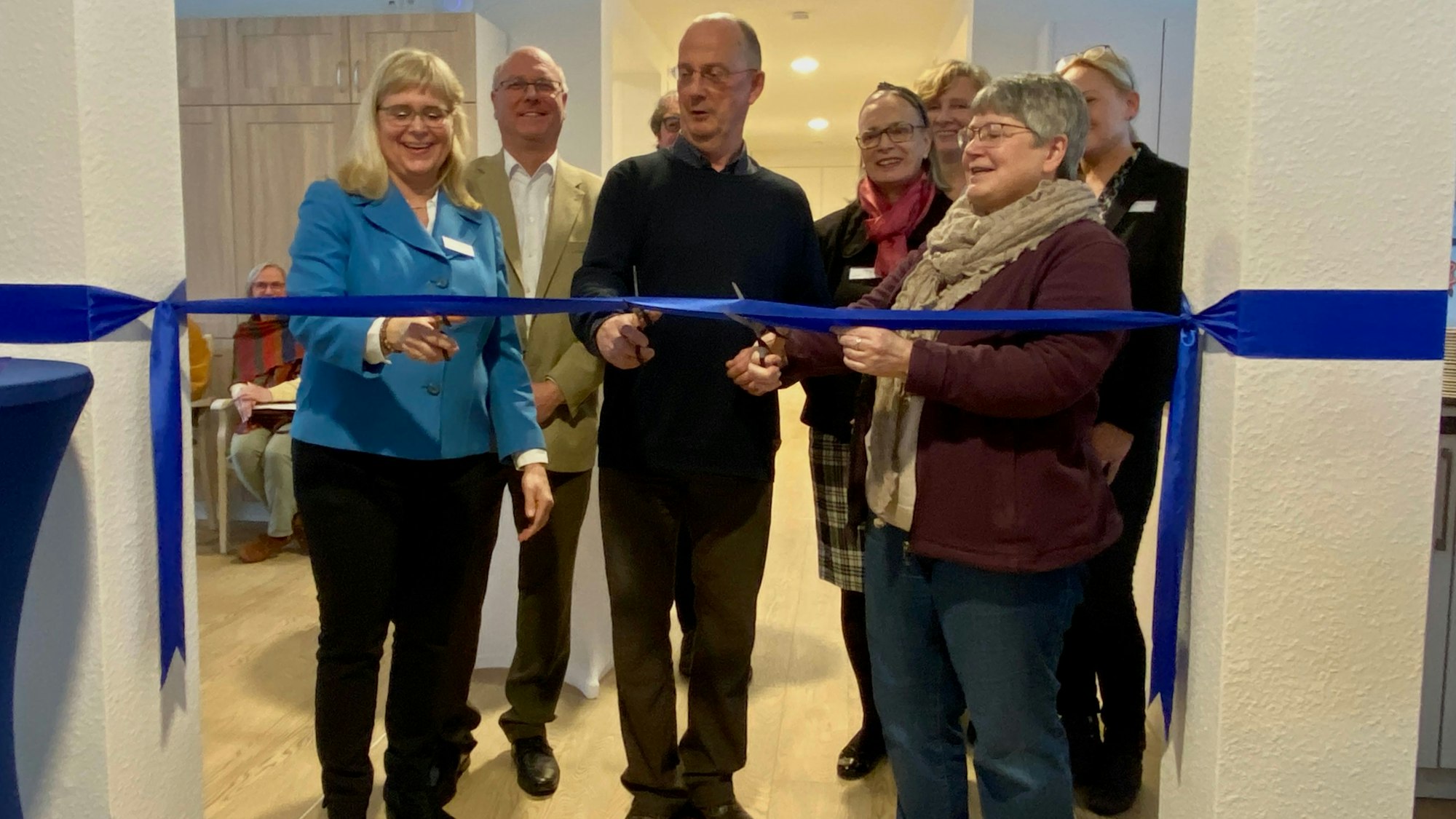 Mehrere Personen durchtrennen ein blaues Band.
