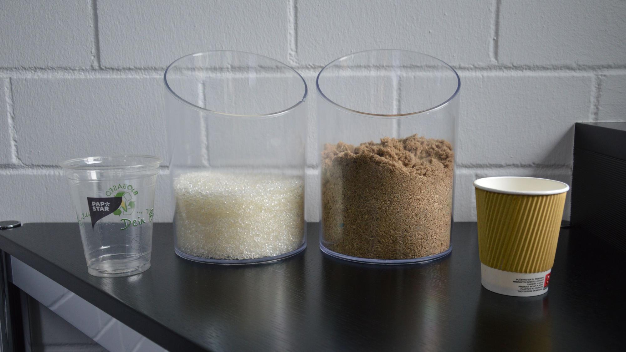 Zwei Becher der Firma Papstar stehen auf ihrem Tisch, daneben die jeweiligen Recyclingprodukte.
