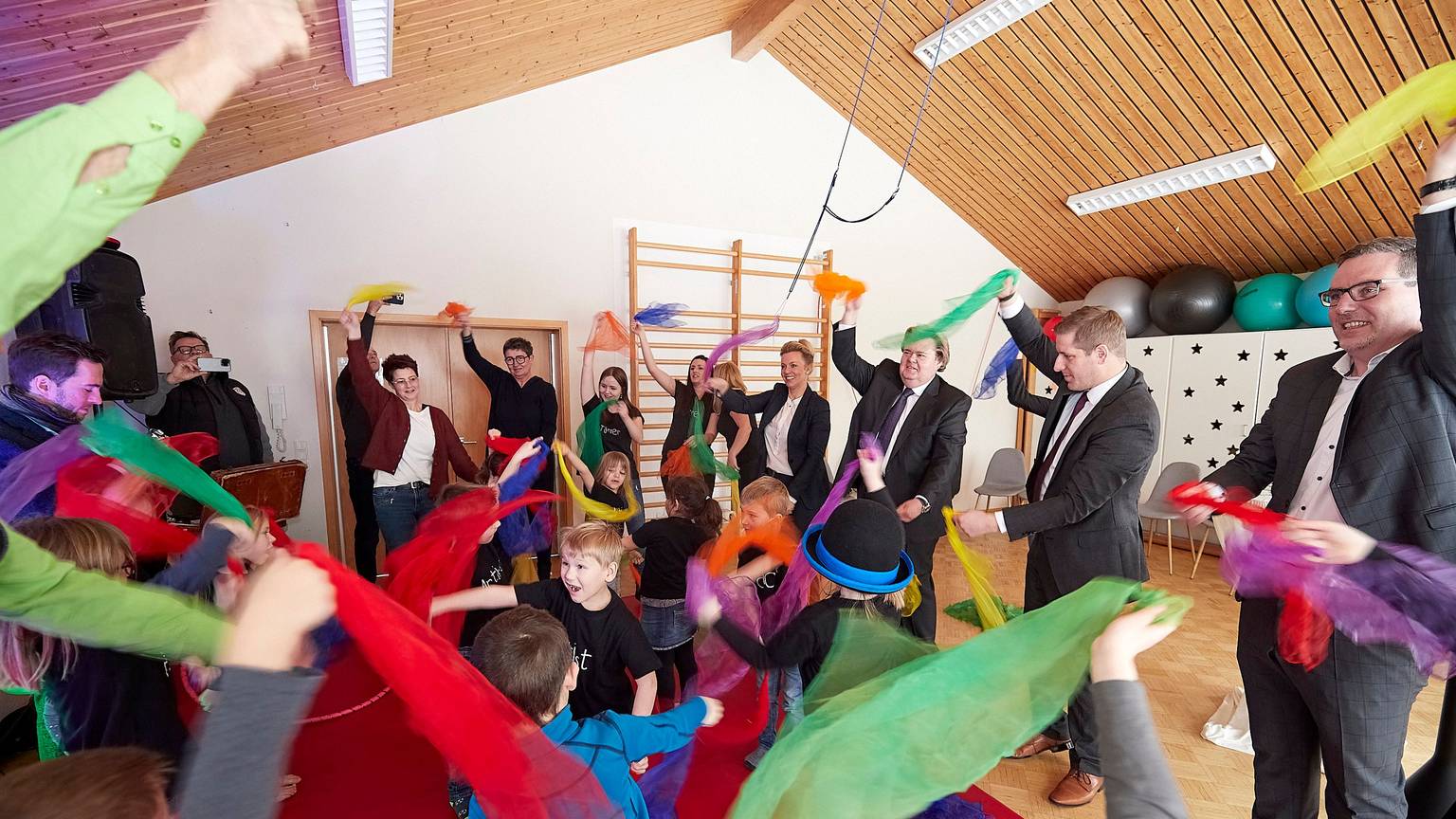 Kindder und Erwachsene schwenken bunte Stofftücher.