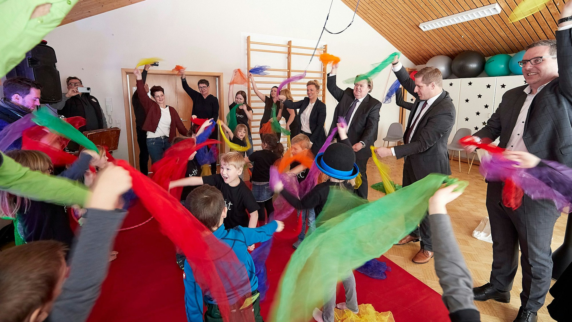 Kindder und Erwachsene schwenken bunte Stofftücher.