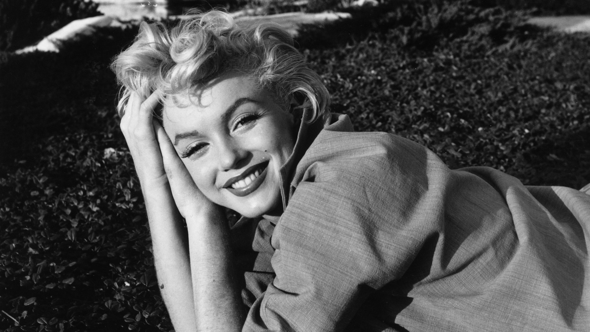 Marilyn Monroe liegend auf der Wiese.
