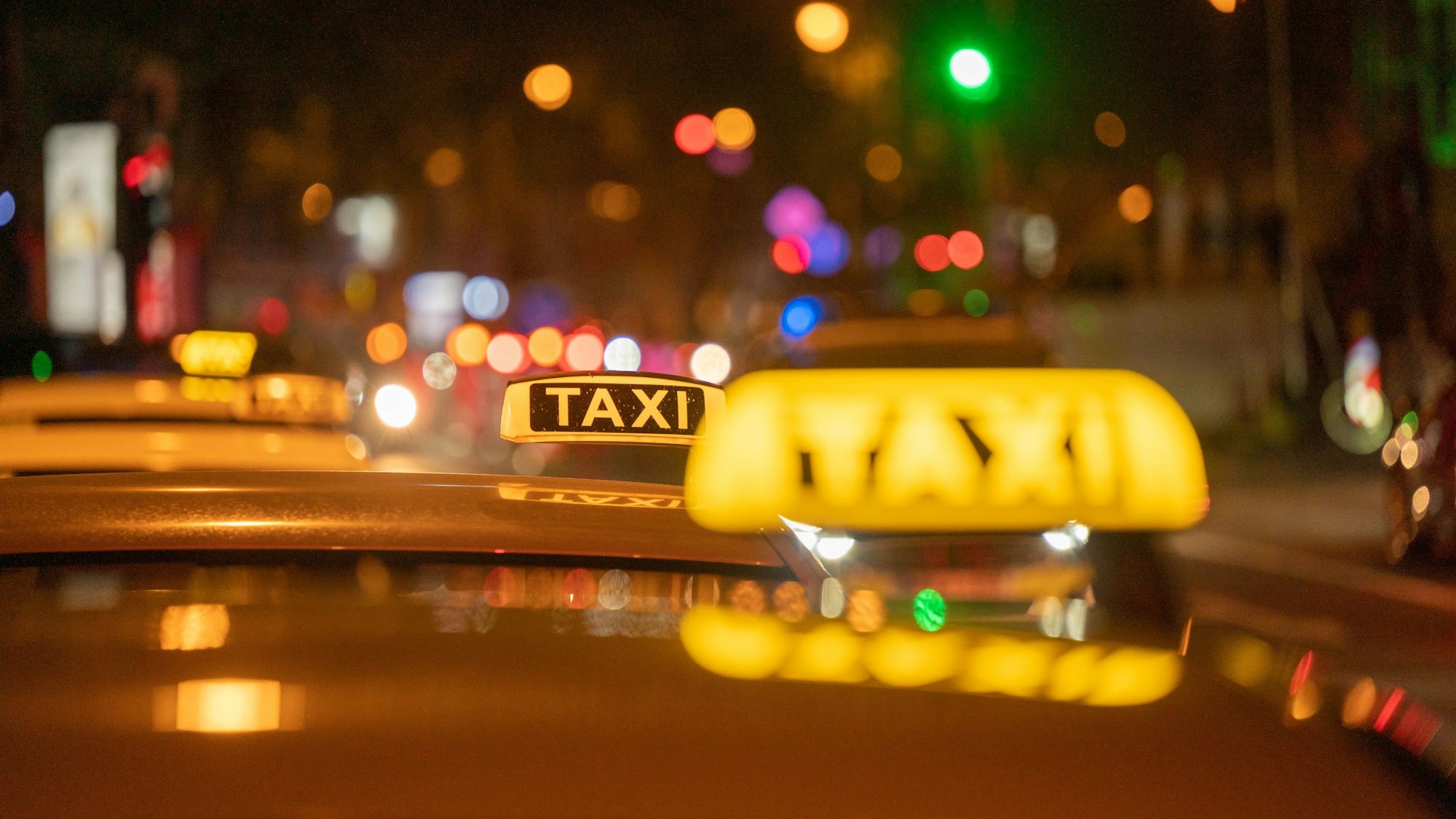 Mehrere Taxis stehen im Dunkeln an den Kölner Ringen und warten auf Kundschaft.