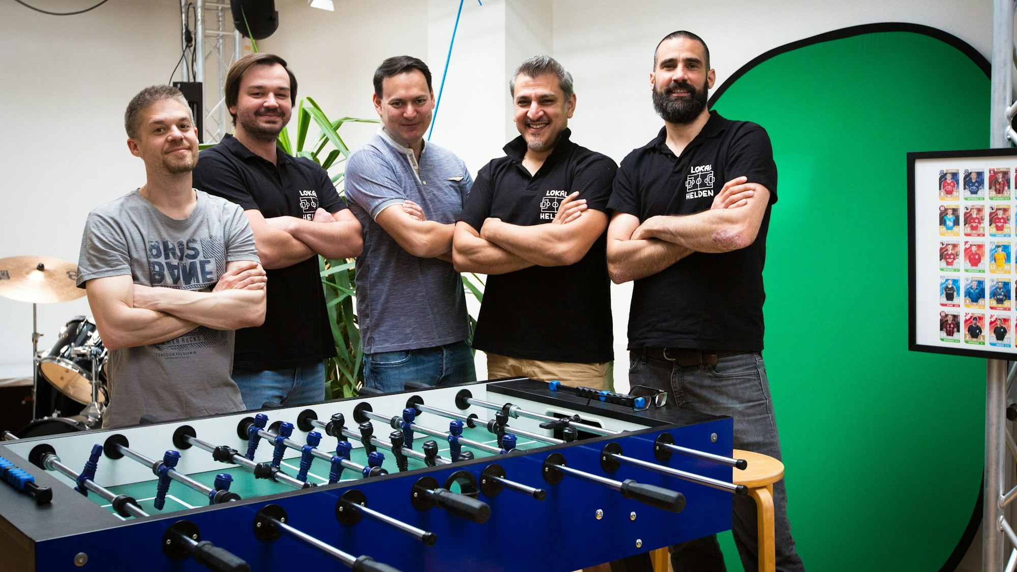 Die fünf Freunde Björn Machel, Viktor Reschetnikow, Marco Ng, Stergios Boucouras und Kevin Latak stecken hinter der Fußballkarten-App. Das Foto zeigt sie vor einem Kicker.