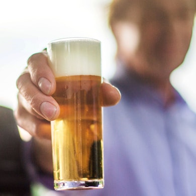 Ein Mann hält ein Kölschglas in der Hand.