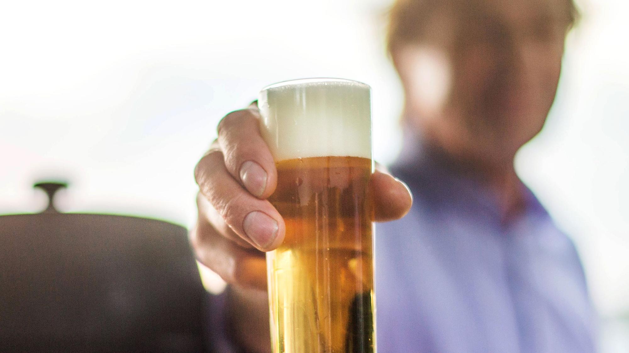 Ein Mann hält ein Kölschglas in der Hand.