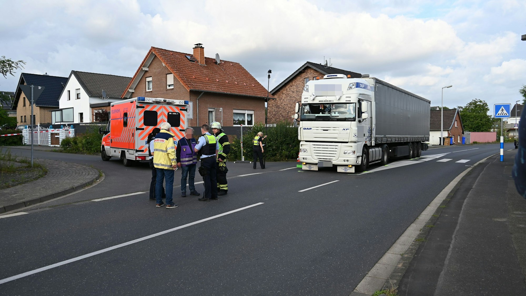 Ein Lkw steht auf der Straße, ein Rettungswagen daneben. Ein paar Menschen stehen davor.