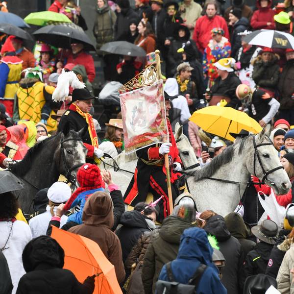Eine Gruppe zu Pferd reitet beim Rosenmontagszug durch die Menge.