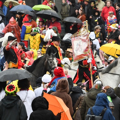 Eine Gruppe zu Pferd reitet beim Rosenmontagszug durch die Menge.
