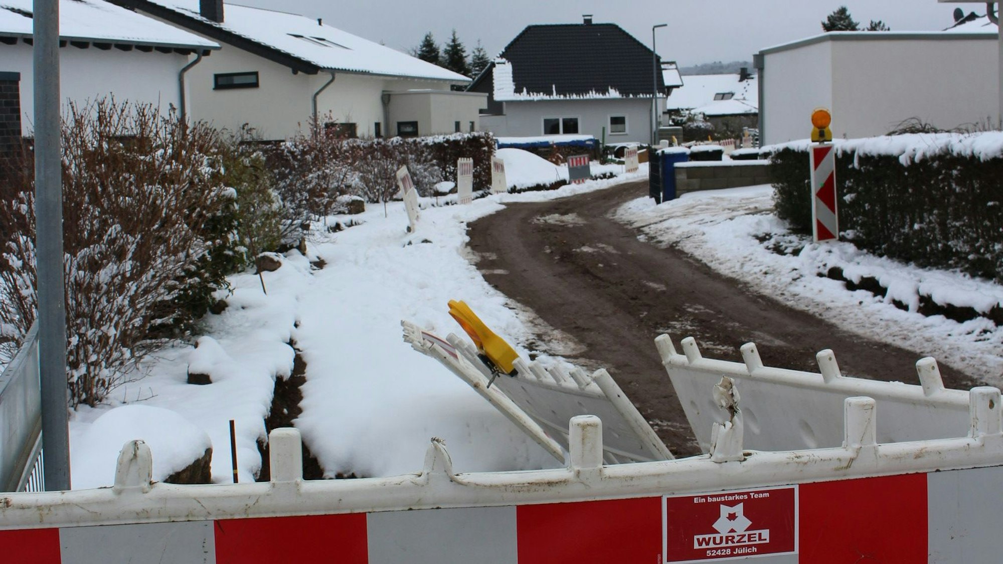 Straßenabsperrungen stehen am Straßenrand. Am Straßenrand liegt ebfalls Schnee.