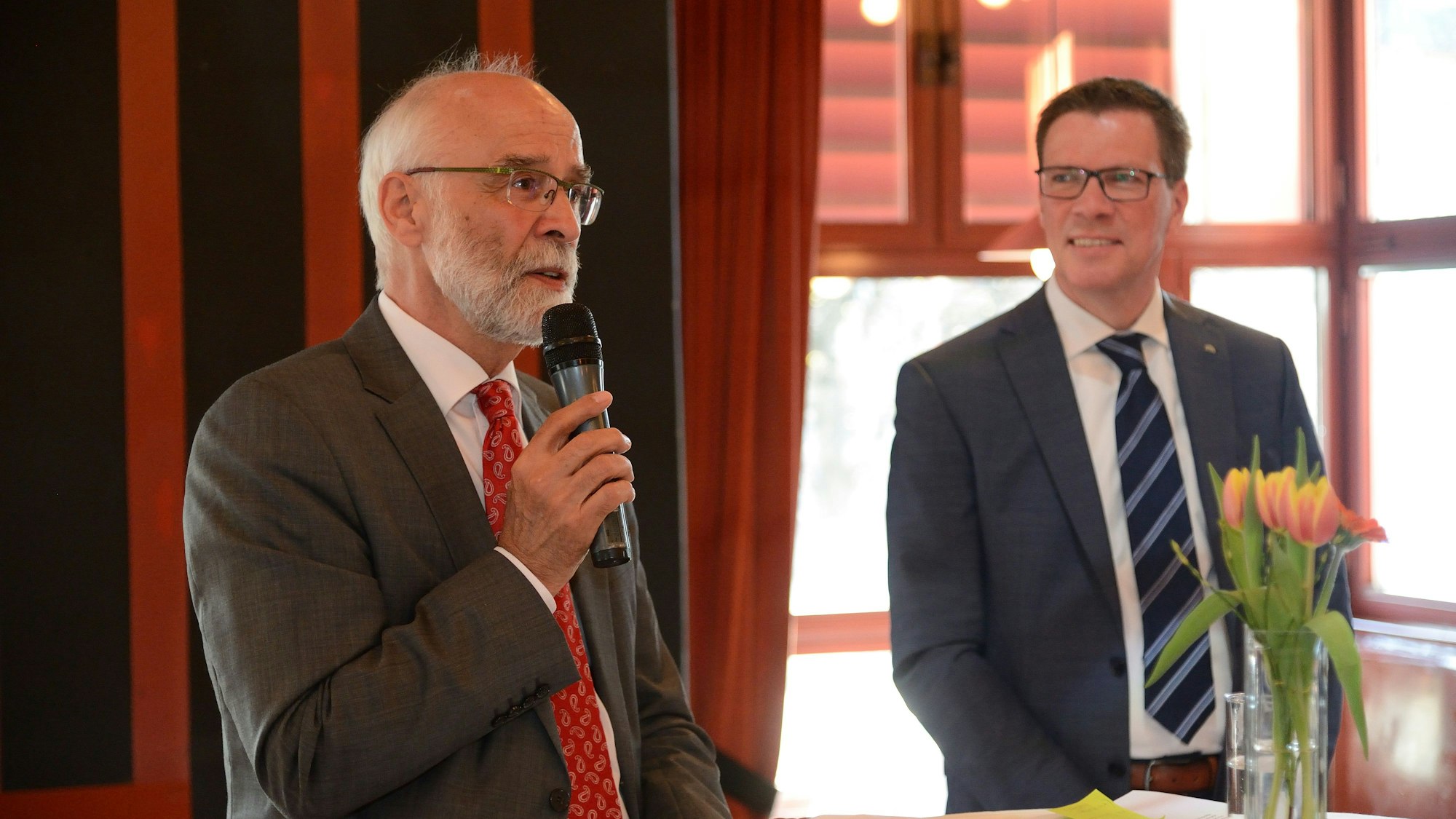 Ulrich Heimann steht neben Landrat Stephan Santelmann mit Mikro in der Hand.