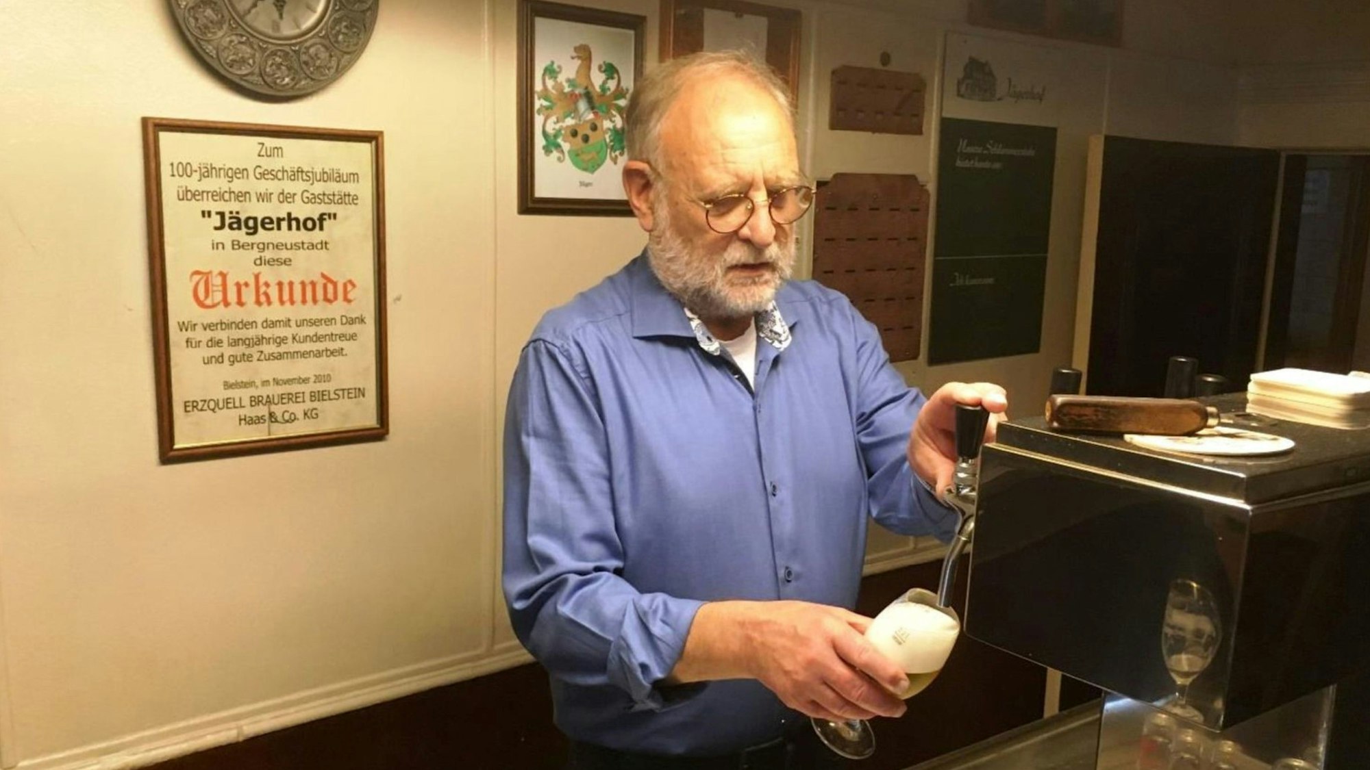 Zu sehen ist ein Mann am Zapfhahn einer Gastwirtschaft.